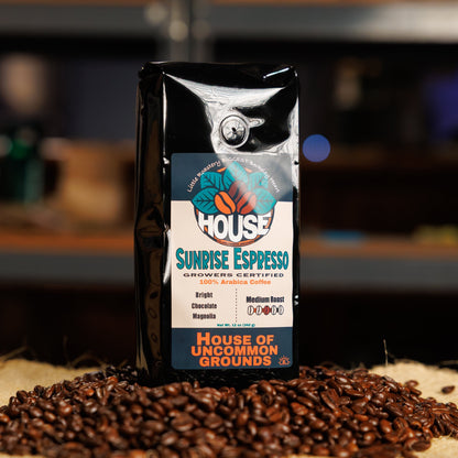 Bag of Sunrise Espresso coffee from House of Uncommon Grounds on a bed of roasted beans