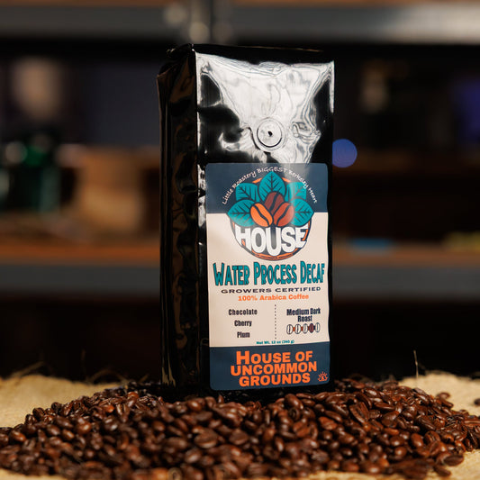 Bag of Water Process Decaf coffee from House of Uncommon Grounds on a bed of roasted beans